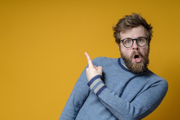 Seltsamer bärtiger Mann mit Brille zeigt mit einem Zeigefinger auf einen leeren Platz