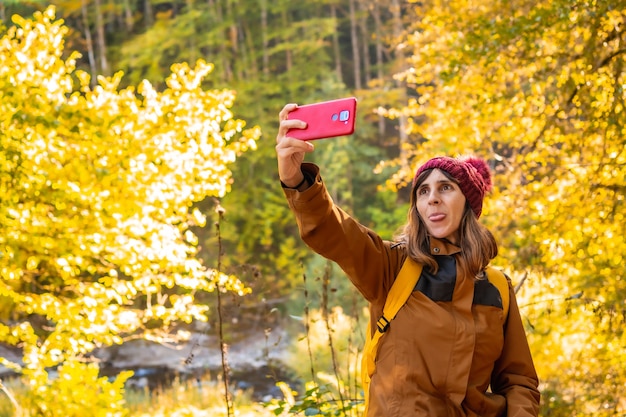 Selva de Irati o en otoño, estilo de vida, una joven excursionista sacando un selfie sacando la lengua en el bosque. Ochagavía, norte de Navarra en España, Selva de Irati