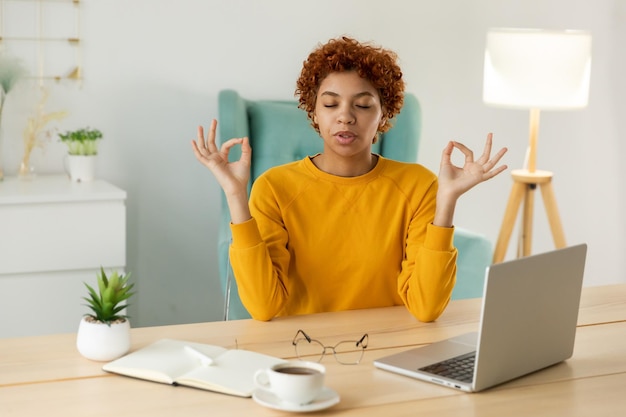 Sem estresse, mantenha a calma, a empresária africana consciente pratica exercícios respiratórios na paz do escritório doméstico