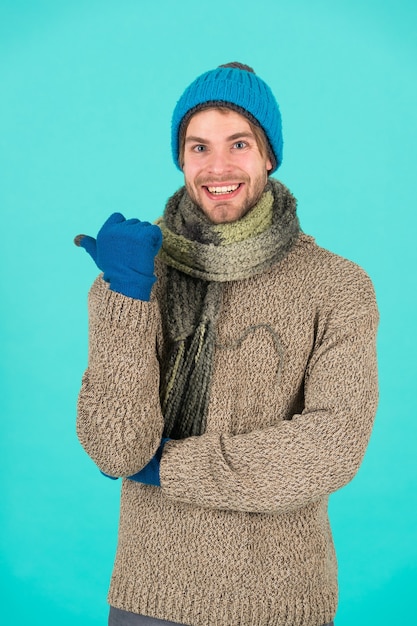 Sem gripe. previsão do tempo de inverno. cara usa roupas quentes. moda masculina de malhas. tecido de malha de homens e acessórios. fundo azul masculino. pobre sem-teto. homem feliz, sentindo frio no inverno.