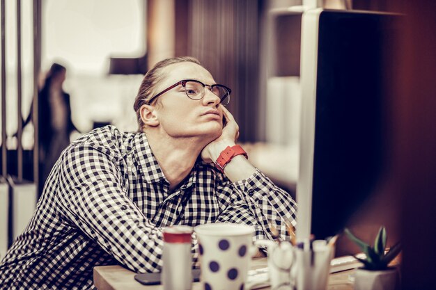 Sem juros. Homem cansado pressionando os lábios enquanto olha para a tela do computador