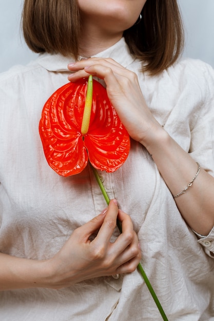 Sem rosto retrato de jovem mulher segurando flor vermelha paz lírio (Spathiphyllum wallisii)