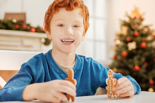 Sem tempo para preocupações. garoto ruivo emocional sorrindo enquanto se diverte e brinca com os bonecos de gengibre em casa.