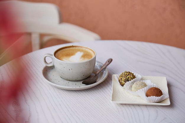 Sem trufas veganas de açúcar sem assar farinha e leite Xícara de cappuccino na mesa de madeira ao ar livre no terraço do café Coffee break