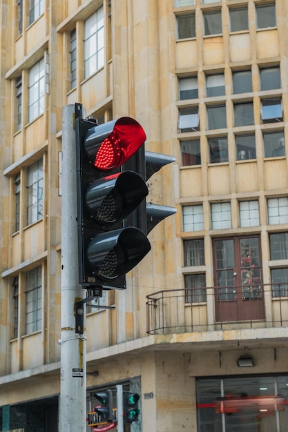 Foto semáforo negro con luz roja encendida en la ciudad de pereira-colombia. edificio marrón