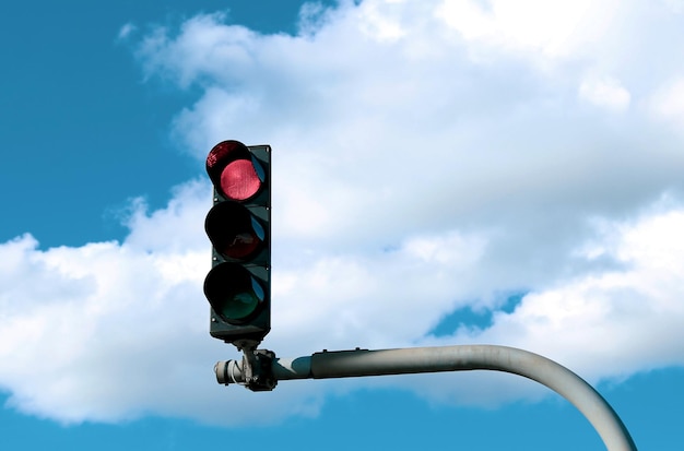 Semáforo en rojo en la calle contra el cielo azul con nubes blancas