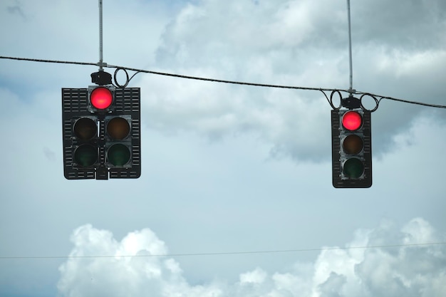 Semáforos de parada de color rojo brillante por encima de la calle sobre fondo de cielo azul