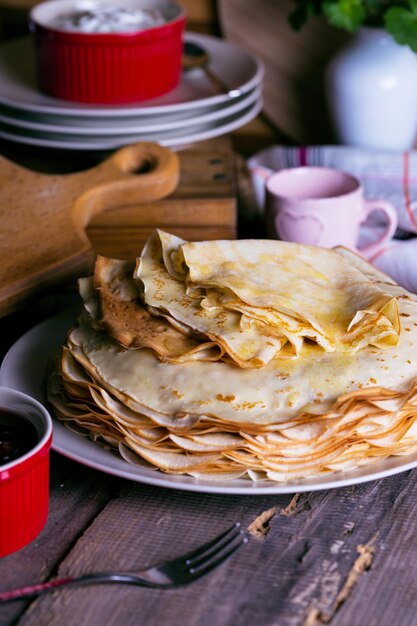 Semana de maslenitsa y panqueques. Plato lleno de panqueques de tradición rusa con crema agria en el platillo