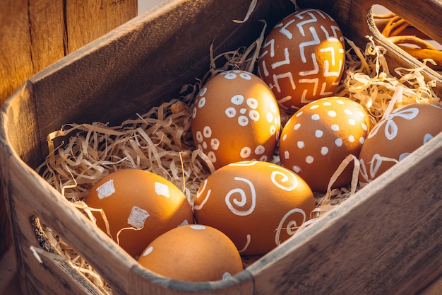 Semana Santa en el campo. Texturas naturales de granja con cálidos tonos de luz solar. Huevos marrones con patrones blancos