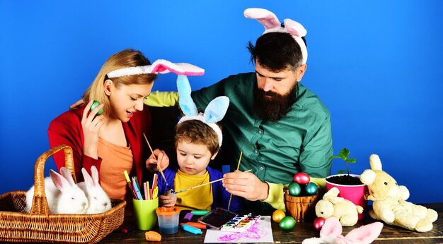 Semana Santa tradición familiar madre padre e hijo en orejas de conejo pintando huevos preparándose para las vacaciones