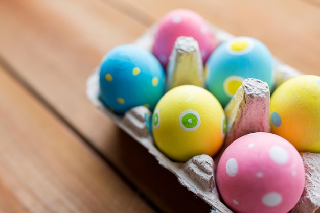 semana santa, vacaciones, tradición y concepto de objeto - cierre de huevos de pascua de colores en caja de huevos o superficie de madera de cartón