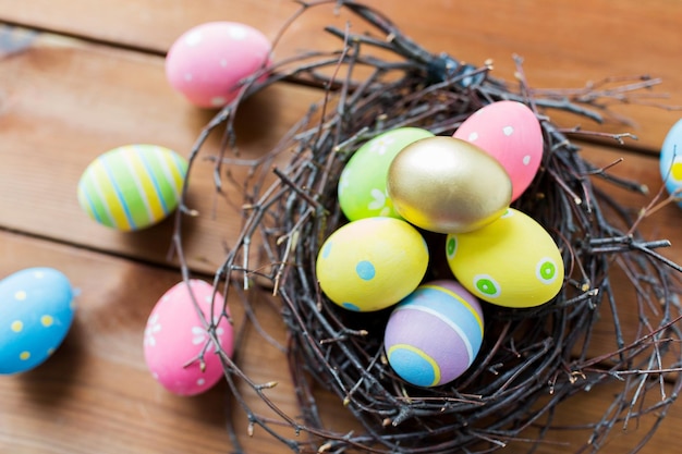 semana santa, vacaciones, tradición y concepto de objeto - cierre de huevos de pascua de colores en el nido en la superficie de madera