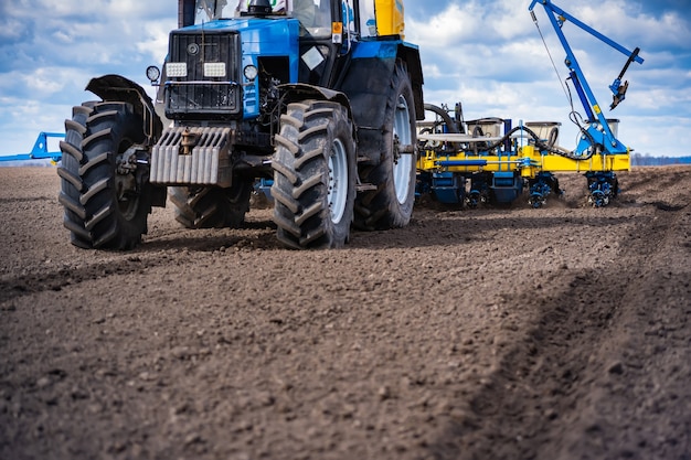 Foto semeando o trabalho no campo na primavera. trator com semeadora.