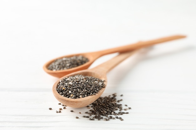 Sementes de chia e colheres de pau em branco de madeira