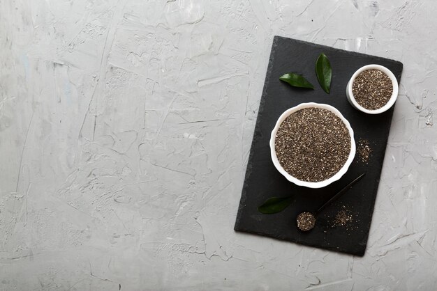 Sementes de chia em tigela e colher em fundo colorido Salvia hispanica saudável em tigela pequena Superalimento saudável