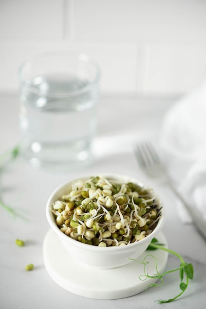 Sementes de feijão verde germinadas e um copo de água fresca, close-up