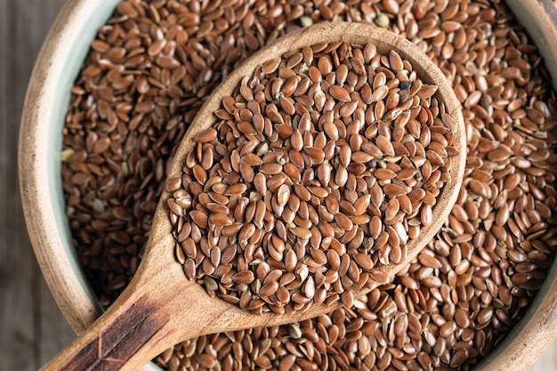 Sementes de linho em uma colher de pau em uma mesa velha