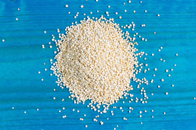 Sementes de quinoa cruas em um backgpound de madeira azul