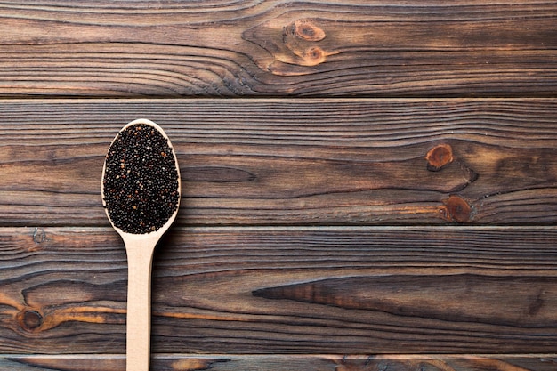 Sementes de quinoa em colher sobre fundo colorido Kinwa saudável em colher pequena Superalimento saudável