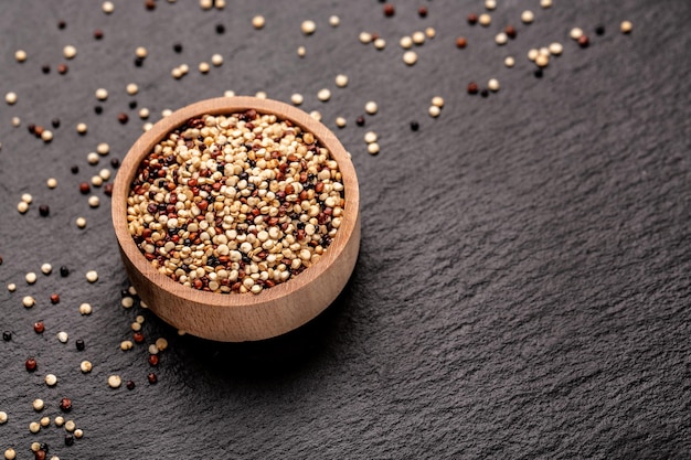 Semilla de quinua cruda entera sin procesar en un plato sobre un fondo de piedra superalimento producto banner menú receta lugar para la vista superior del texto