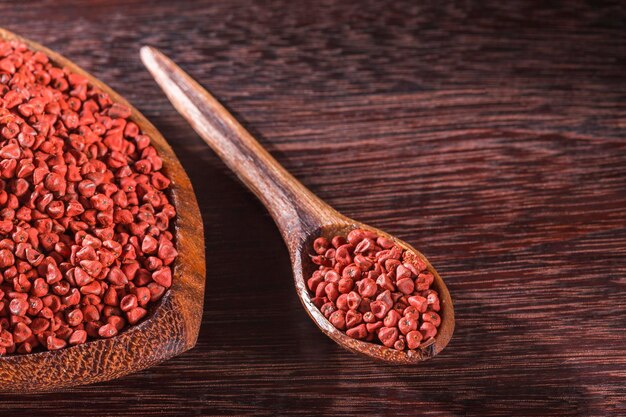 Semillas de achiote en un recipiente sobre fondo de madera Bixa Orellana