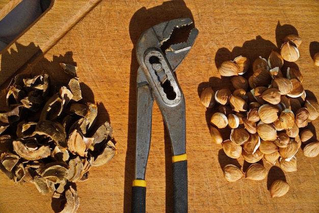 Semillas de albaricoque y hoyos en una tabla de cortar de madera junto a pinzas para dividirlos