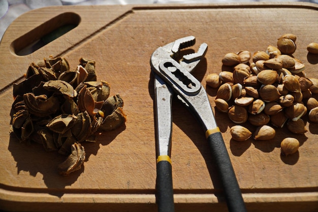 Semillas de albaricoque y hoyos en una tabla de cortar de madera junto a pinzas para dividirlos