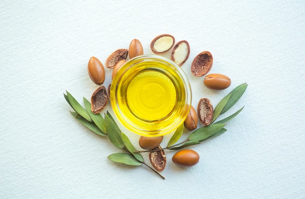 Foto semillas de argán y aceite aislado sobre un fondo blanco. nueces de aceite de argán con planta.