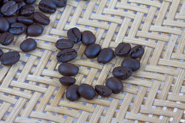 Semillas de café del corazón en el fondo de bambú de madera