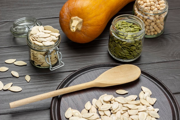 Semillas de calabaza en frascos de vidrio Cuchara de madera y semillas a bordo