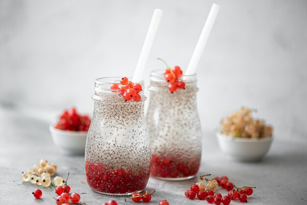 Semillas de chía con agua mineral y bayas en botellas de vidrio.