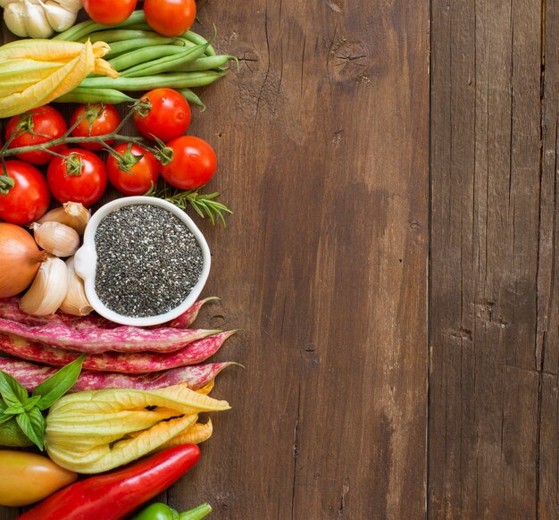 Semillas de chía crudas en un tazón y vista superior de verduras frescas con espacio de copia