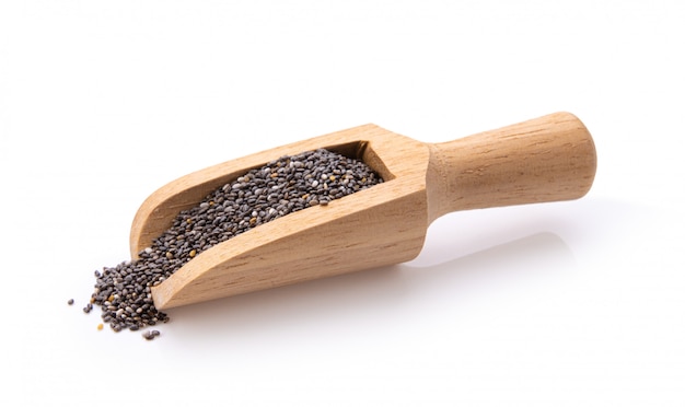 Semillas de Chia en la cucharada de madera aislada con el fondo blanco.