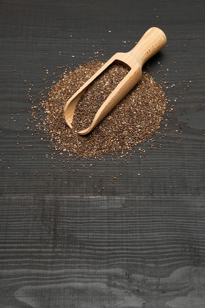 Foto semillas de chía naturales orgánicas y primer plano de cuchara de madera sobre fondo de madera o mesa