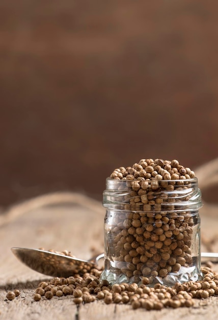 Semillas de cilantro en tarro especias orientales secas estilo rústico mesa de cocina antigua enfoque selectivo