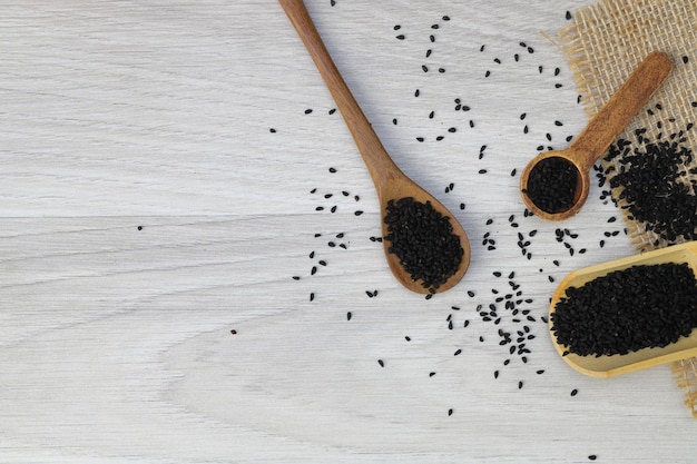 Semillas de comino negro y aceite esencial con cuenco y pala o cuchara de madera Nigella Sativa