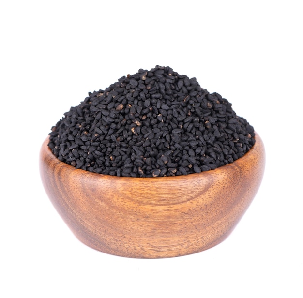 Semillas de comino negro en tazón de madera aislado sobre fondo blanco Montón de semillas de nigella negro Nigella sativa