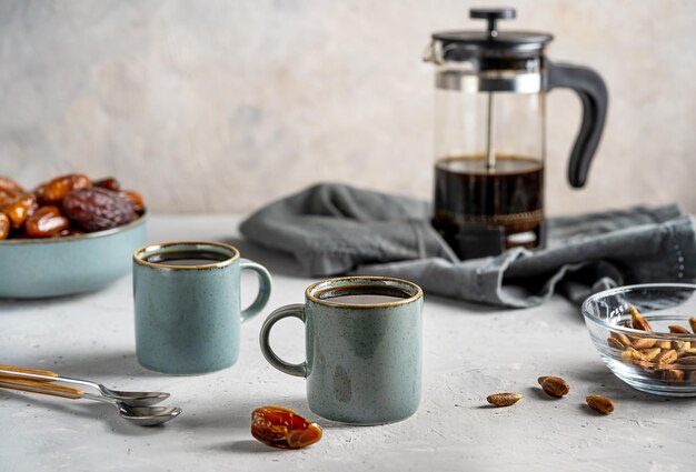 Semillas de dátiles saludables café en dos tazas cafetera con dátiles frutas y semillas sobre fondo gris