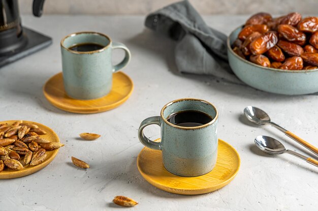 Semillas de dátiles saludables café en dos tazas cafetera con dátiles frutas y semillas sobre fondo gris