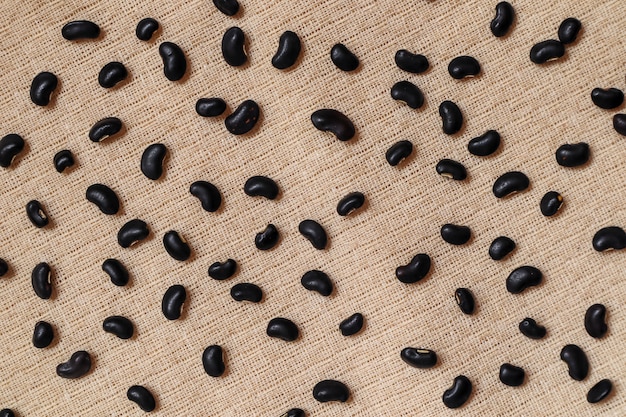 Foto semillas de frijoles negros sobre tela crema