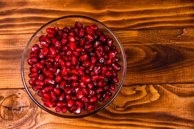 Semillas de la fruta granate en recipiente de vidrio sobre mesa de madera Vista superior