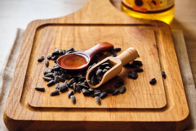 Semillas de girasol y aceite en cuchara de madera sobre fondo de madera