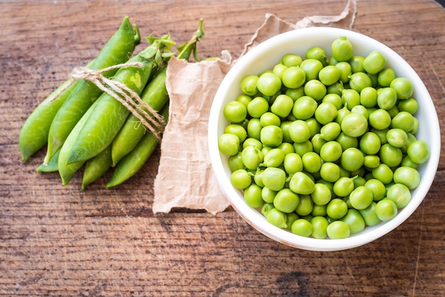 Semillas de guisantes en un recipiente sobre fondo de madera. copia espacio