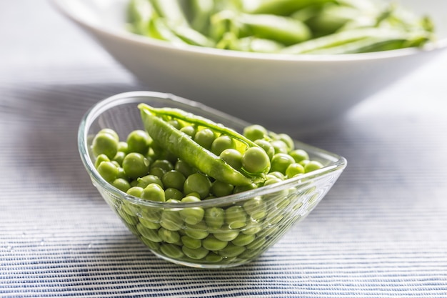 Semillas de guisantes verdes frescas en un recipiente sobre la mesa de la cocina.