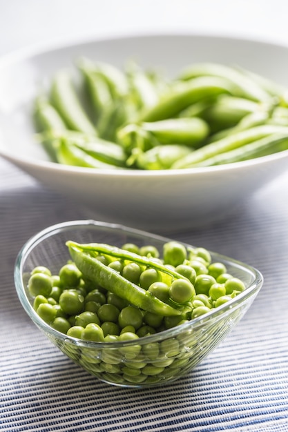 Semillas de guisantes verdes frescas en un recipiente sobre la mesa de la cocina.