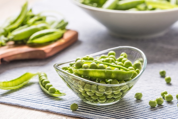 Semillas de guisantes verdes frescas en un recipiente sobre la mesa de la cocina.