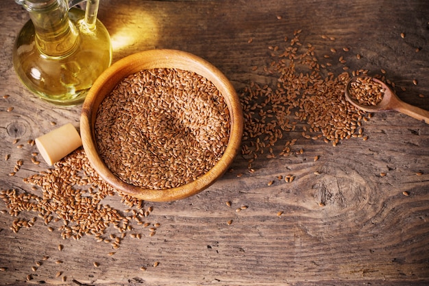 Semillas de lino y aceite de linaza en una jarra de vidrio sobre una mesa de madera