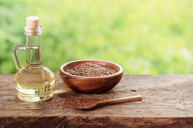 Semillas de lino y aceite de linaza en una jarra de vidrio sobre una mesa de madera