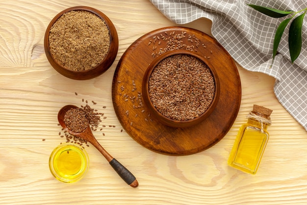 Semillas de lino en una cuchara y recipiente con una botella de aceite de linaza y harina de linaza