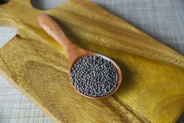 Semillas de mostaza marrón en cuchara de madera